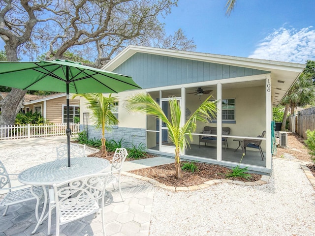 106 E Cedar St, Tarpon Springs, FL 34689 - view of front of property featuring a sunroom, a ceiling fan, fence, a patio area, and outdoor dining area