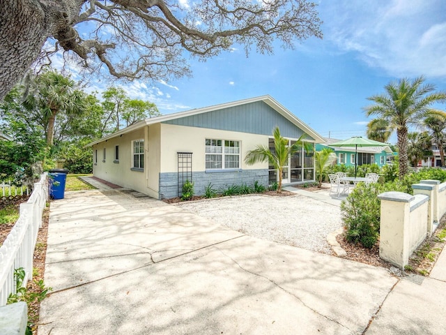 106 E Cedar St, Tarpon Springs, FL 34689 - view of front facade with stone siding, concrete driveway, stucco siding, and a sunroom