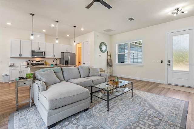 living area featuring light wood-style flooring, baseboards, a ceiling fan, and recessed lighting