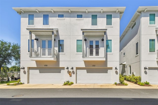 view of front of house with stucco siding, an attached garage, and a balcony