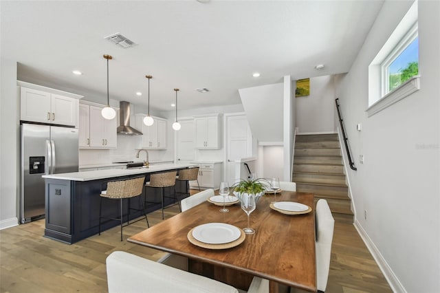 dining room featuring baseboards, light wood-style floors, stairway, and recessed lighting