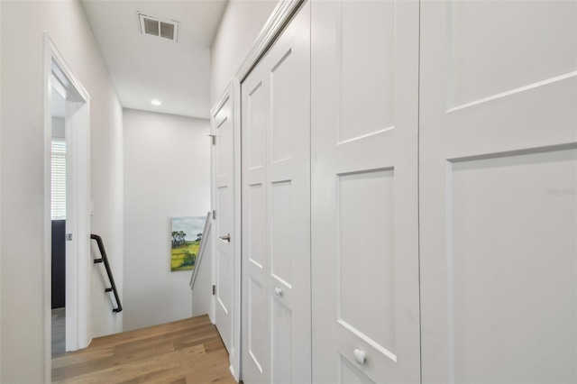corridor with light wood finished floors, recessed lighting, and an upstairs landing