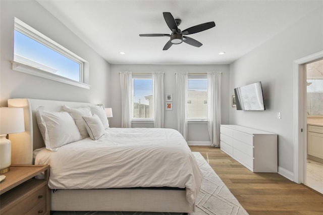 bedroom with light wood finished floors, multiple windows, recessed lighting, connected bathroom, and a ceiling fan