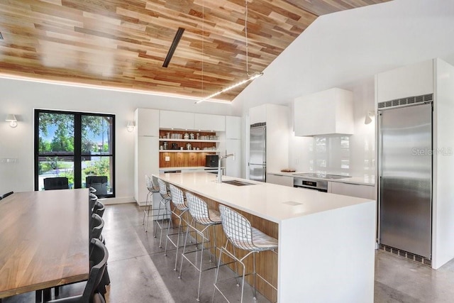 kitchen with built in fridge, a sink, wood ceiling, concrete floors, and white cabinets