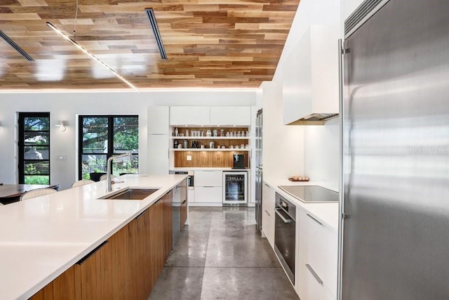 kitchen featuring appliances with stainless steel finishes, a sink, modern cabinets, beverage cooler, and wood ceiling