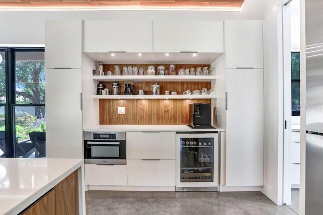 bar area featuring beverage cooler, oven, and finished concrete flooring