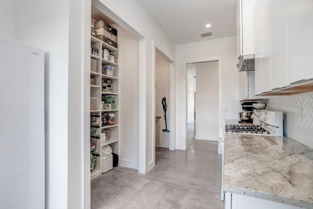hallway featuring concrete floors and baseboards
