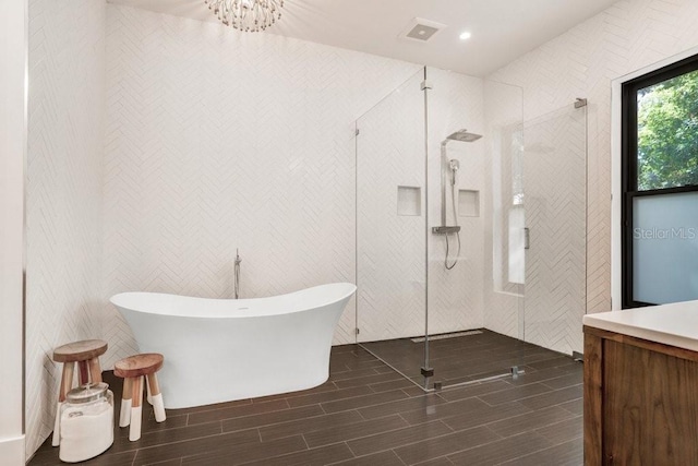 full bath with wood finish floors, a stall shower, a freestanding bath, vanity, and recessed lighting
