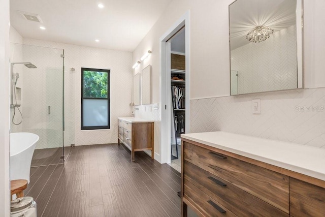full bathroom with a shower stall, vanity, wood finished floors, a freestanding bath, and a walk in closet