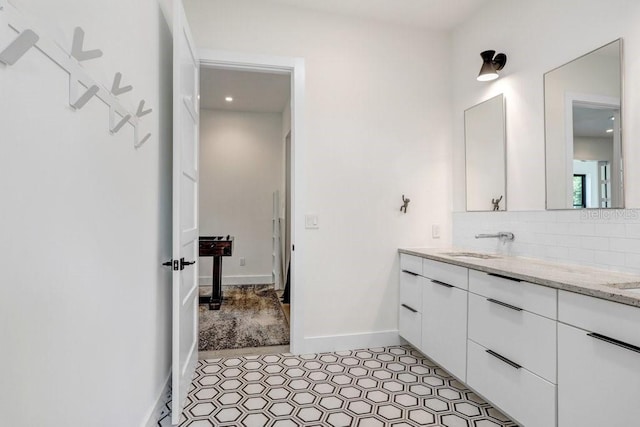 full bathroom featuring backsplash, double vanity, and baseboards