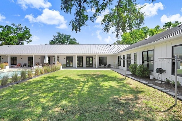 back of property featuring board and batten siding, a lawn, metal roof, french doors, and a patio