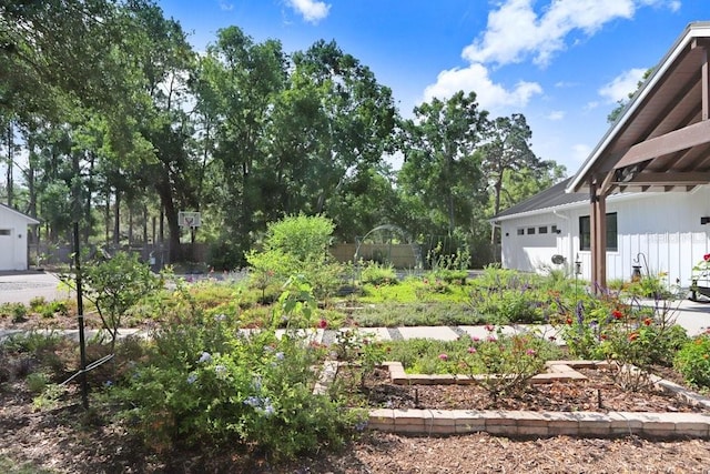 view of yard featuring fence, a vegetable garden, and an attached garage