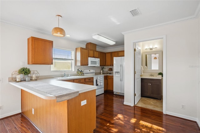 kitchen featuring white appliances, a peninsula, a sink, light countertops, and dark wood finished floors