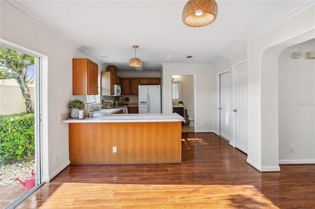 kitchen featuring white appliances, light countertops, wood finished floors, a sink, and ornamental molding