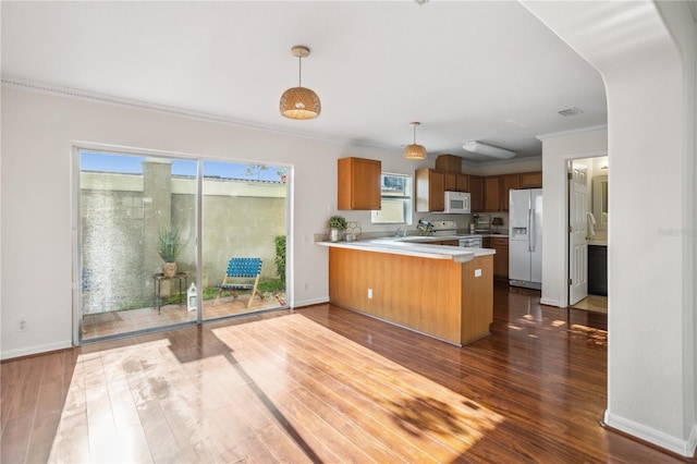 kitchen featuring white appliances, a peninsula, light countertops, crown molding, and dark wood-style flooring