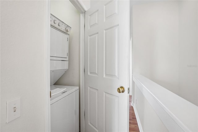 clothes washing area featuring stacked washer / dryer and wood finished floors