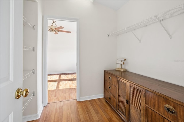 spacious closet with light wood-style floors and a ceiling fan