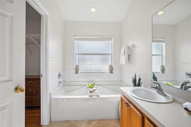 full bath featuring vanity, a garden tub, recessed lighting, and a walk in closet