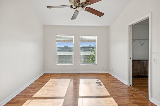 unfurnished bedroom with wood finished floors, a walk in closet, baseboards, and a closet