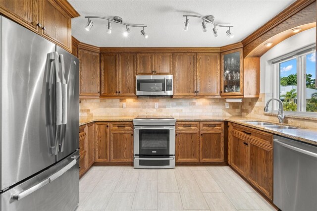 261 Kentucky Ave, Crystal Beach, FL 34681 - kitchen featuring stainless steel appliances, a sink, brown cabinetry, and light stone countertops