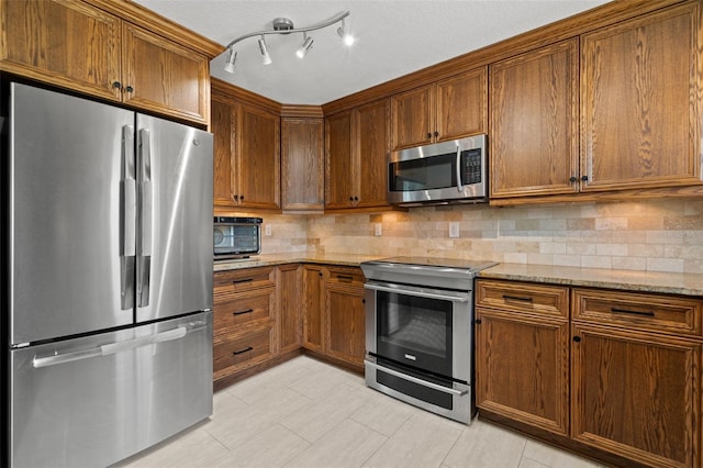 261 Kentucky Ave, Crystal Beach, FL 34681 - kitchen with appliances with stainless steel finishes, decorative backsplash, light stone countertops, and brown cabinets