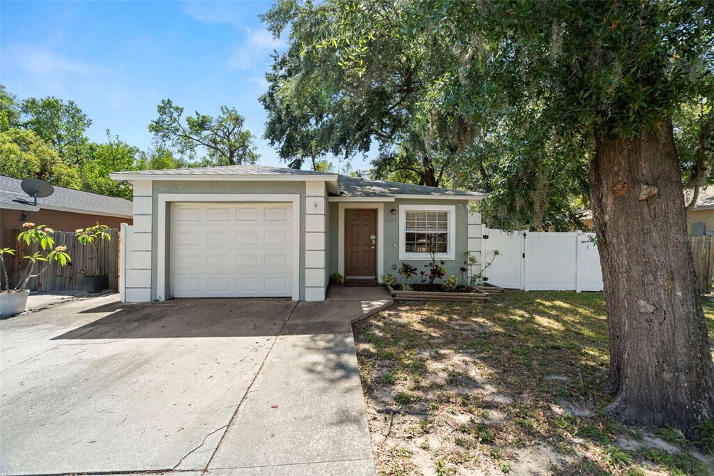 6208 Rolling Hammock, Tampa, FL 33610 - view of front of house featuring concrete driveway, a garage, fence, a gate, and stucco siding