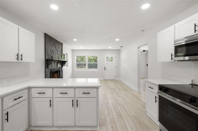 2157 20th Ave SW, Largo, FL 33774 - kitchen with stainless steel appliances, recessed lighting, a peninsula, white cabinets, and light wood-type flooring