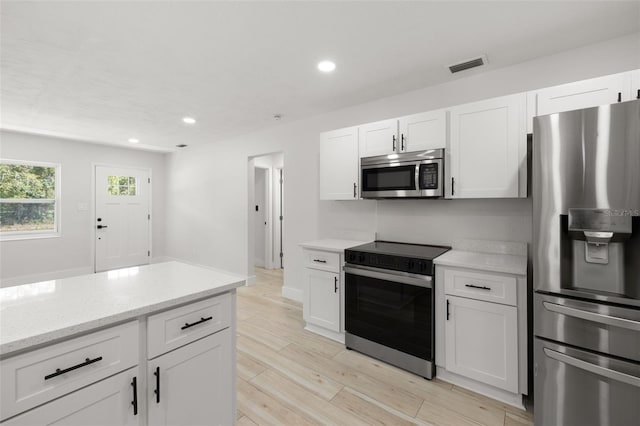2157 20th Ave SW, Largo, FL 33774 - kitchen featuring appliances with stainless steel finishes, white cabinetry, light wood-type flooring, recessed lighting, and light stone countertops