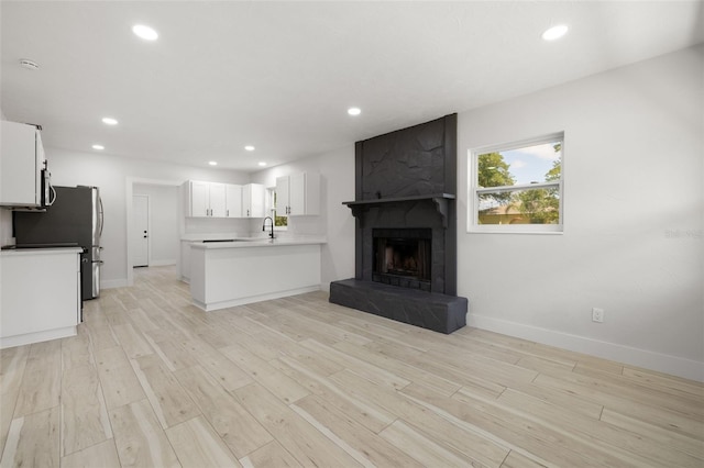 2157 20th Ave SW, Largo, FL 33774 - unfurnished living room featuring a sink, recessed lighting, light wood finished floors, baseboards, and a fireplace