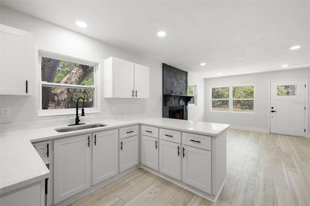 2157 20th Ave SW, Largo, FL 33774 - kitchen featuring a sink, a large fireplace, a peninsula, recessed lighting, and white cabinets