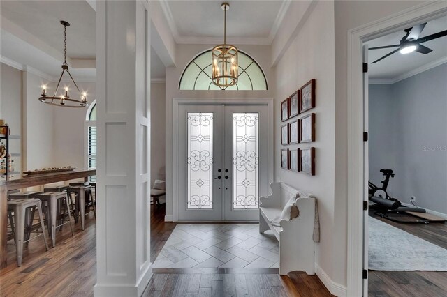 foyer entrance with a chandelier, ornamental molding, wood finished floors, french doors, and baseboards