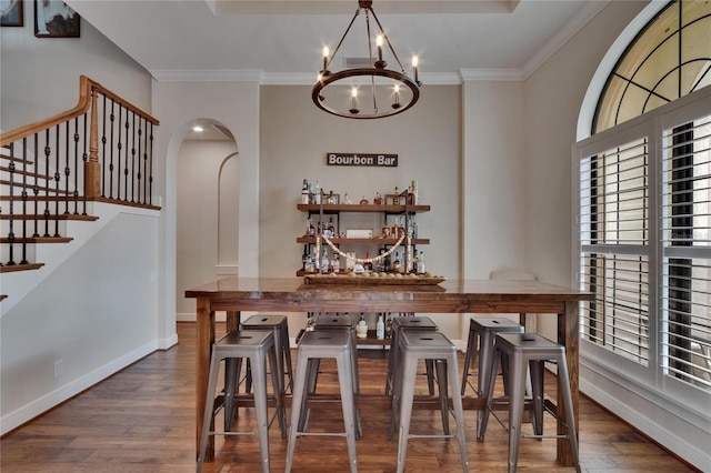 dining space with wood finished floors, a chandelier, arched walkways, plenty of natural light, and ornamental molding