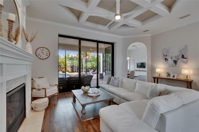 living area with arched walkways, coffered ceiling, a premium fireplace, beamed ceiling, and crown molding