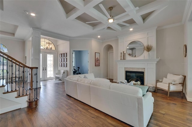 living area with coffered ceiling, dark wood-style floors, stairs, beamed ceiling, and a glass covered fireplace