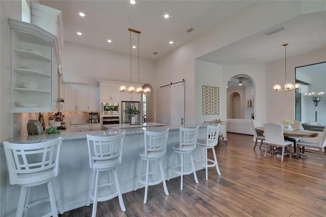 kitchen with stainless steel appliances, a chandelier, arched walkways, white cabinetry, and recessed lighting