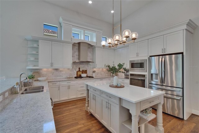 kitchen with open shelves, appliances with stainless steel finishes, a sink, wall chimney exhaust hood, and tasteful backsplash