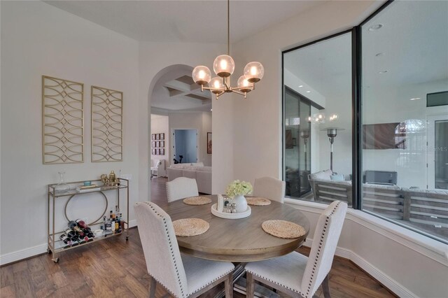 dining area with wood finished floors, arched walkways, a chandelier, coffered ceiling, and baseboards
