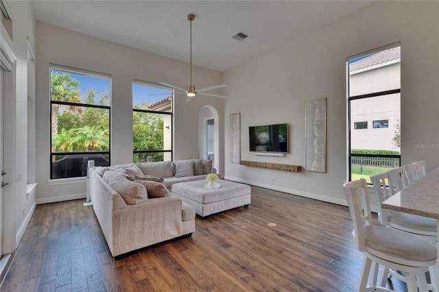 living room featuring dark wood-style floors, plenty of natural light, and arched walkways