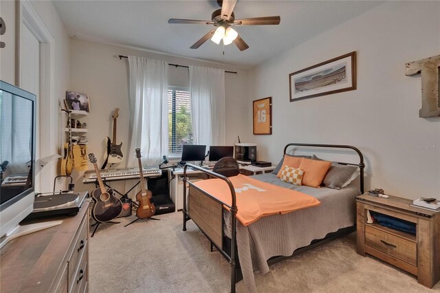 bedroom with light carpet, ceiling fan, and an office area