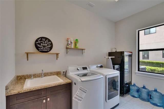 washroom featuring separate washer and dryer, cabinet space, and light tile patterned floors