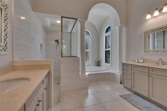 bathroom with decorative columns, two vanities, walk in shower, a bath, and tile patterned floors