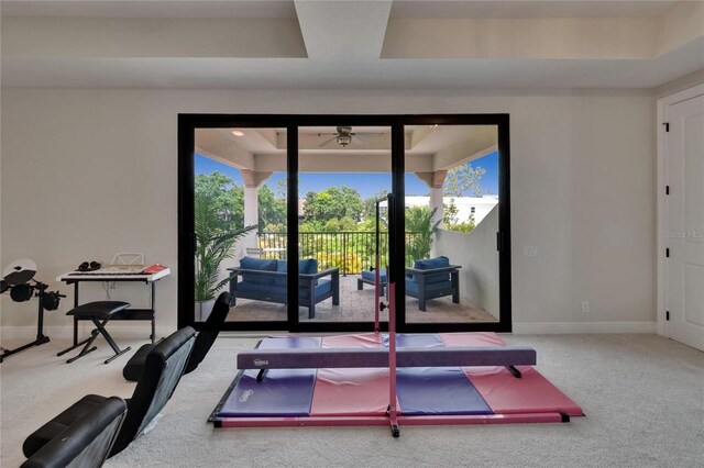 exercise room with carpet, a ceiling fan, a raised ceiling, and baseboards