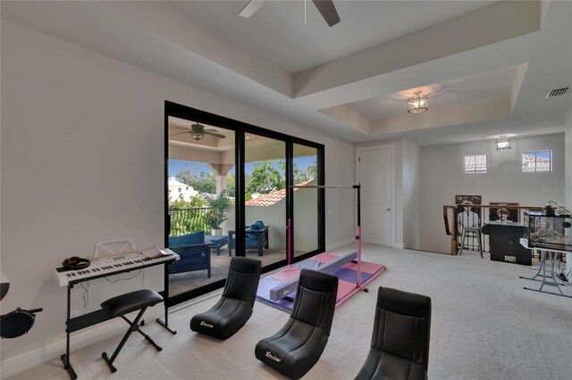 workout area featuring ceiling fan, carpet flooring, a raised ceiling, and baseboards