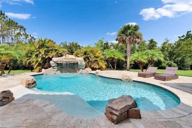 swimming pool with a patio and view of wooded area