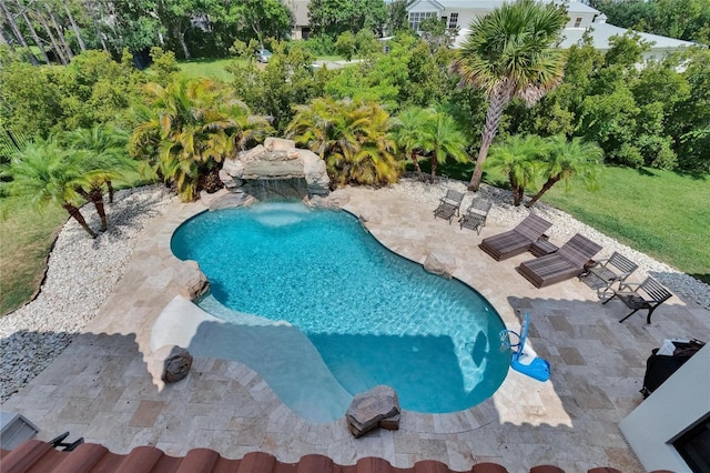 swimming pool with a patio area and view of scattered trees