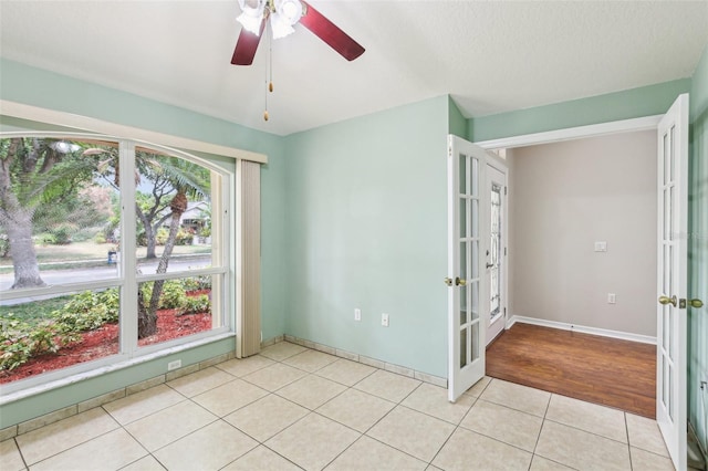 10150 Heather Sound Dr, Tampa, FL 33647 - empty room with french doors, light tile patterned floors, a ceiling fan, and baseboards