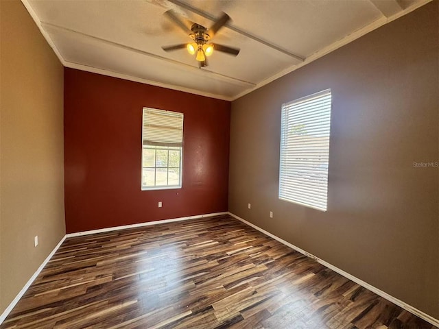 empty room featuring crown molding, a ceiling fan, dark wood-type flooring, and baseboards