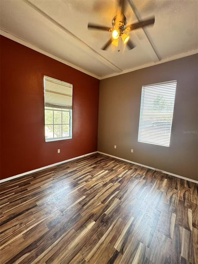 unfurnished room with dark wood-type flooring, a ceiling fan, baseboards, and ornamental molding