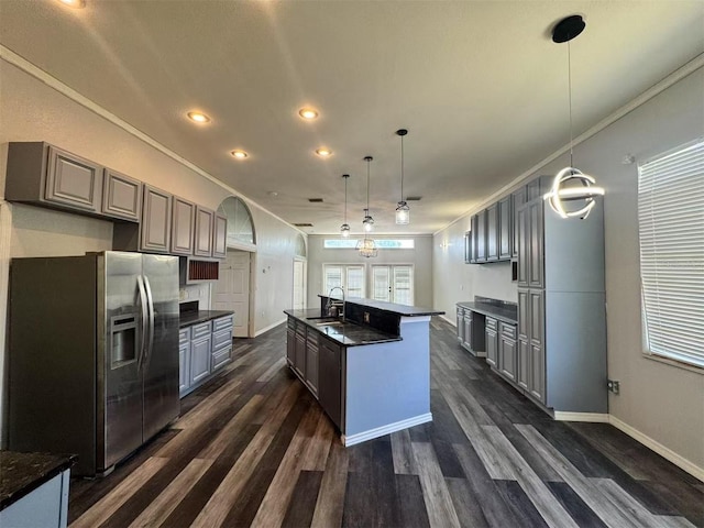 kitchen with stainless steel fridge with ice dispenser, dark countertops, dark wood-type flooring, crown molding, and gray cabinetry