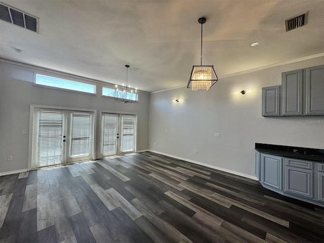 unfurnished living room with baseboards, dark wood finished floors, a chandelier, french doors, and crown molding